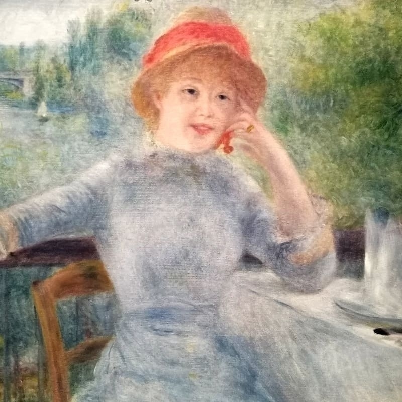 Uma jovem está sentada na varanda do restaurante Fournaise, apoiada numa mesa posta. Ela segura na mão cerejas penduradas na orelha. Ela usa um chapéu de palha com uma fita vermelha, da mesma cor do carmim que contorna sua boca sorridente. Seu cabelo é loiro. Seu braço direito estendido sobre a grade marca uma divisão com a paisagem ao fundo. Dá pra ver uma vela rápida navegando no rio Sena perto da ponte ferroviária.